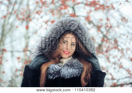 beautiful smiling girl on background of snowy trees. Winter portrait. coat with a hood