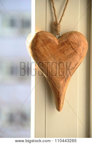 Beautiful wooden heart hanging on the edge of window with outside view of city. Space for your text.