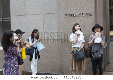 asian girls take photographs of each other near tiffany's in new york