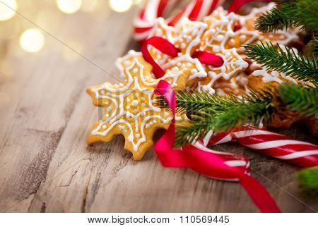 Christmas Holiday Background with Gingerbread cookies, Candy Cane and evergreens border over wooden table. Christmas and New year food. Christmas decoration and sweets on wood background