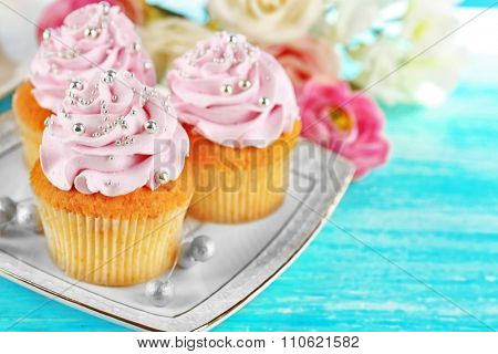Cake with sugar paste flowers and cupcakes, on light background