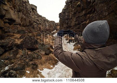 Tourist taking photso of the crack between tectonic plates in Pingvellir national park Iceland