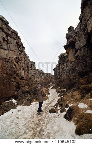 Independent Tourist walking through the crack between tectonic plates in Thingvellir national park, Iceland