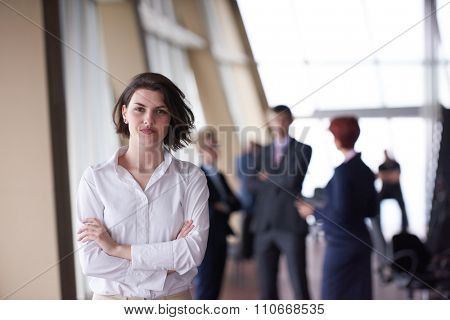 Smilling young business woman in front her team blured in background. Group of young business people. Modern bright  startup office interior.
