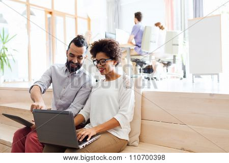 business, startup, technology and people concept - happy international creative team with laptop and tablet pc computer at office
