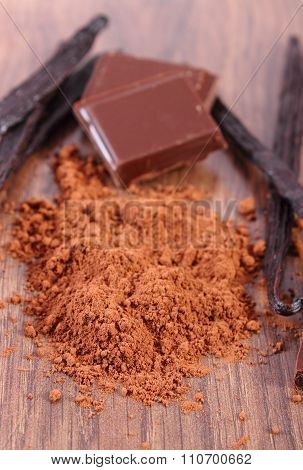 Powdery Cocoa, Dark Chocolate, Fragrant Vanilla Sticks On Wooden Surface