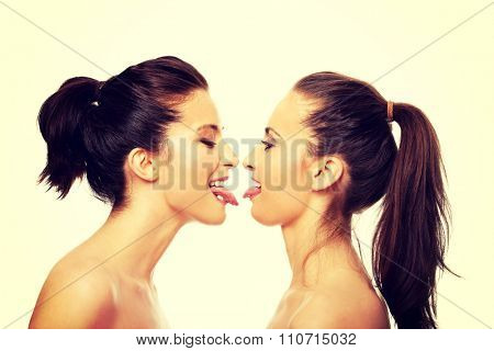 Two attractive women with make up showing their tongs.