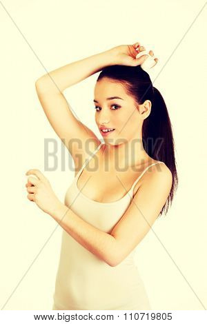 Young smiling woman applying anti perspirant.