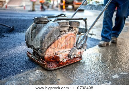 Asphalt Worker At Road Construction Site With Compactor Plate And tools