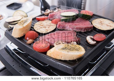 Steaks, Garlic Bread And Mushrooms On The Raclette  Cooking