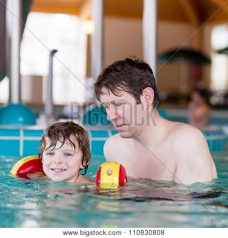 Cute little boy and his father having fun in swimming pool