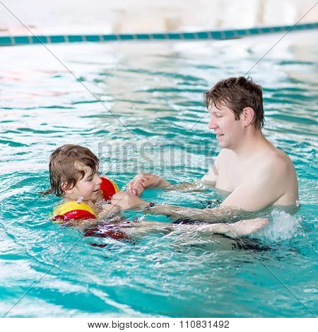 Little kid boy and his father swimming in an indoor pool