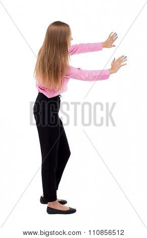 back view of business woman pushes wall.  Isolated over white background. Blond girl in green skirt pushing something heavy right. girl office worker in black trousers shoves something in front of him