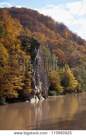 Spring landscape of the mountains with golden trees on the river mouth