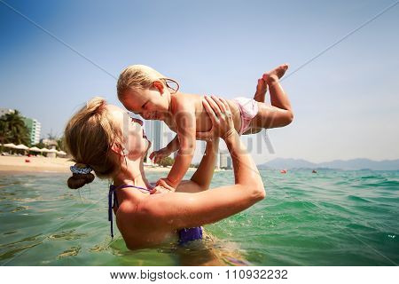 Side-view Mother In Sea Holds In Arms Small Daughter Smile