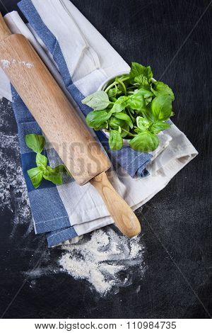 Rolling pin, vegetablers and flour on a black background.