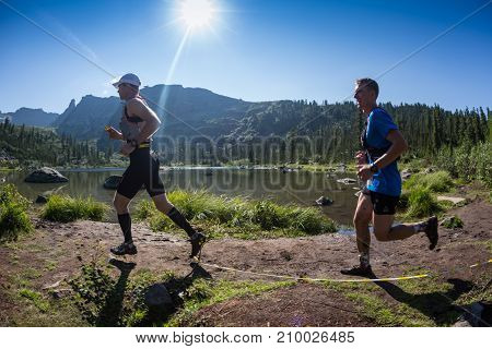 ERGAKI, RUSSIA - AUGUST 05 2017: Several athletes run through the mountains, participants trailing the SKAYRANFEST competition on August 5, 2017 in the Ergaki National Park, Russia