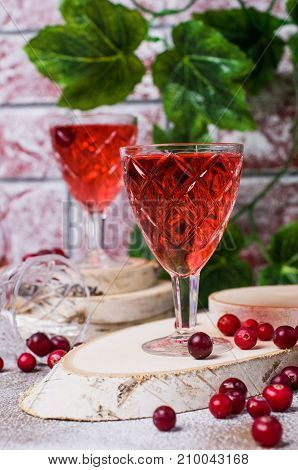 Transparent red drink with cranberries on a wooden background. Selective focus.