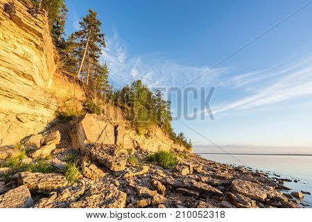 Sunset on the beach. Limestone cliff in the sea under blue sky and white clouds. Kesselaid a small island in Estonia. Nordic countries Europe
