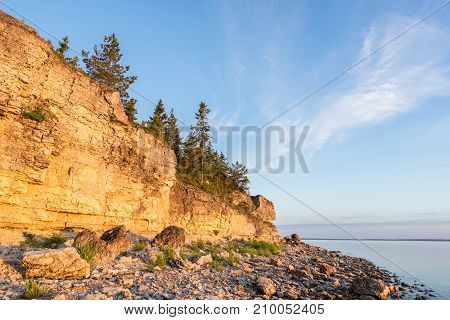 Sunset on the beach. Limestone cliff in the sea under blue sky and white clouds. Kesselaid a small island in Estonia. Nordic countries Europe