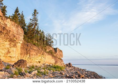 Sunset on the beach. Limestone cliff in the sea under blue sky and white clouds. Kesselaid a small island in Estonia. Nordic countries Europe