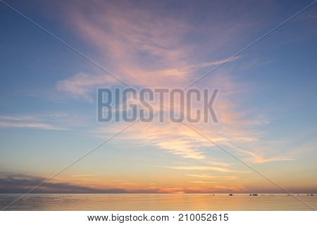 Evening sunlight on coast pink clouds blue sky reflection on water. Beach in summer. Seaside natural environment. Shore in Kesselaid small island in Estonia. Nature Reserve in North Europe