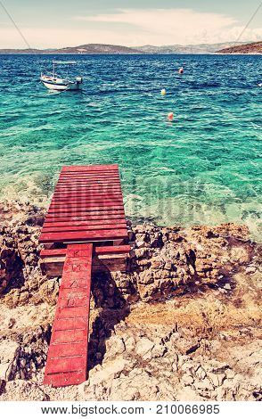 Beautiful Mediterranean sea Solta Croatia. Summer vacation. Springboard turquoise water and little boat. Red photo filter.