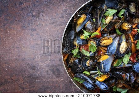 Traditional barbecue Italian blue mussel in red wine sauce as top view in a casserole with copy space left