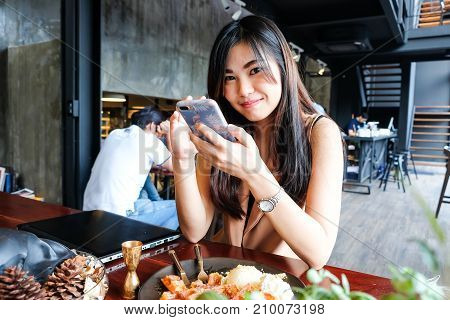 Women Texting On Moblie Phone While Sitting In Modern Cafe