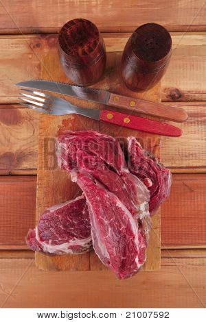 savory: red raw beef meat steak on wooden cutting board prepared for roasting