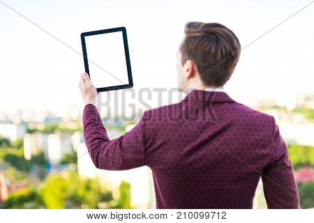 Young Serious Businessman In Red Suit And Shirt With Tie Stand On The Roof With Empty Tablet