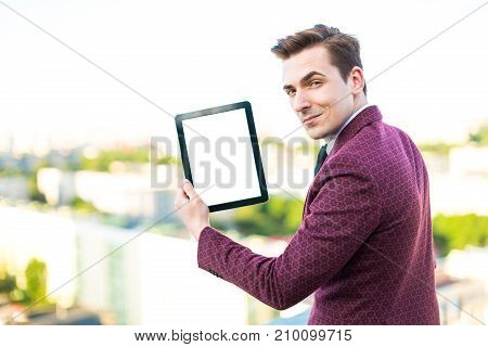 Young Serious Businessman In Red Suit And Shirt With Tie Stand On The Roof With Empty Tablet