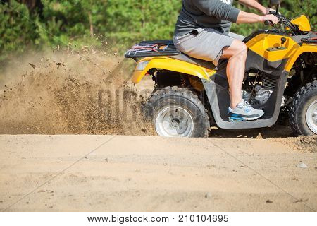 An Atv Quadbike Get Stuck In A Sandy Road Near Forest And Having Wheel-spin Making A Spray Of Sand