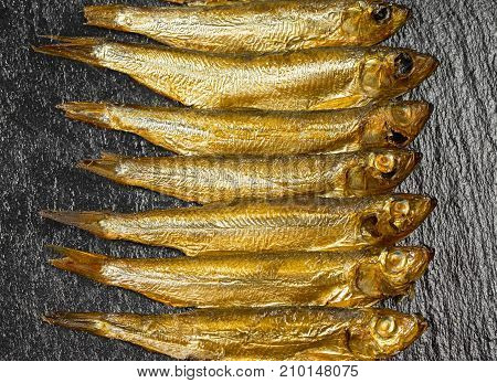 arrangement with lots of fresh smoked sprats on dark stone slab