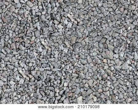 Seamless texture of the beautiful macadam. Gray black brown beige red stones are evenly scattered on the surface