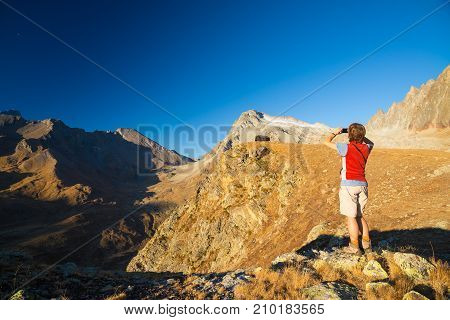 One Person Looking At View High Up On The Alps. Expasive Landscape, Idyllic View At Sunset. Rear Vie