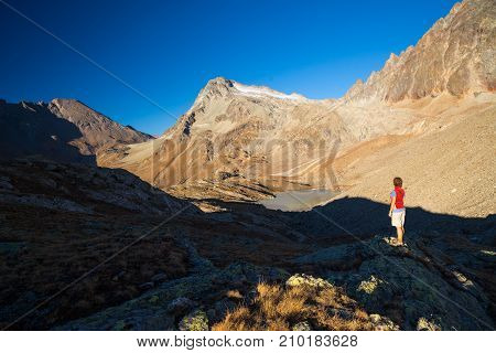 One Person Looking At View High Up On The Alps. Expasive Landscape, Idyllic View At Sunset. Rear Vie