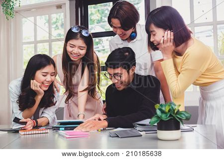 Group of five young euphoric students watching exam results in a laptop in a table of an university campus bar.