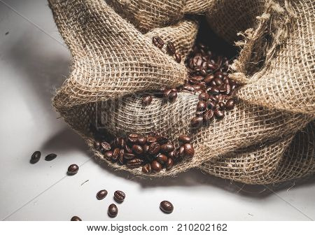 on a white background lie aromatic coffee beans in a coarse sack