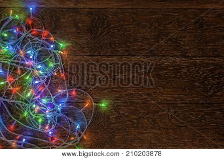 Burning LED garland on a dark wooden background. Preparation for Christmas and New Year concept.