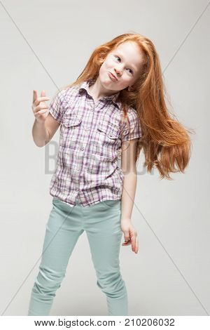 Adorable Cute Redhead Little Girl In Plaid Shirt, Bright Blue Trousers And White Boots