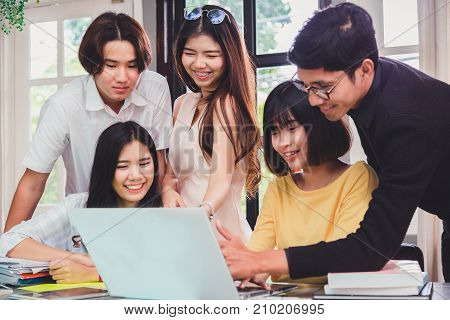 Group of young euphoric students watching exam results in a laptop in a table of an university .