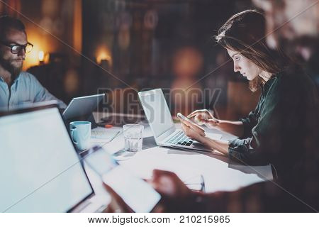 Business team working process photo.Group of young coworkers working together at night modern office loft.Blurred background.Horizontal mock up. Flares and reflections effect