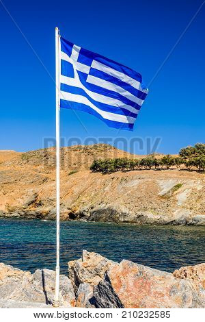 Waving greek flag on mast. resort Panormos in Crete island Greece