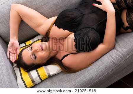 A big and beautiful woman relaxing in lingerie on the Sofa.