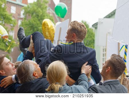 STOCKHOLM SWEDEN - JUN 13 2017: Family throwing graduating student in the air to celebrate at the dance school Balettakademien June 13 2017StockholmSweden
