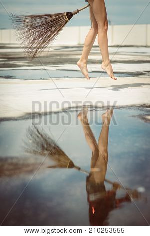 Slender legs beautiful witch on a flying broomstick. Modern Halloween costume