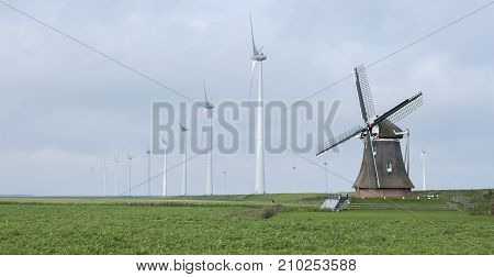 old windmill goliath at roodeschool in the dutch province of groningen between row of modern wind turbines
