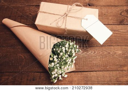 Bouquet of camomile field wrapped in kraft paper on a wooden table