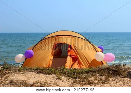 Camping tent in wilderness by the seaside, decorating balloons.